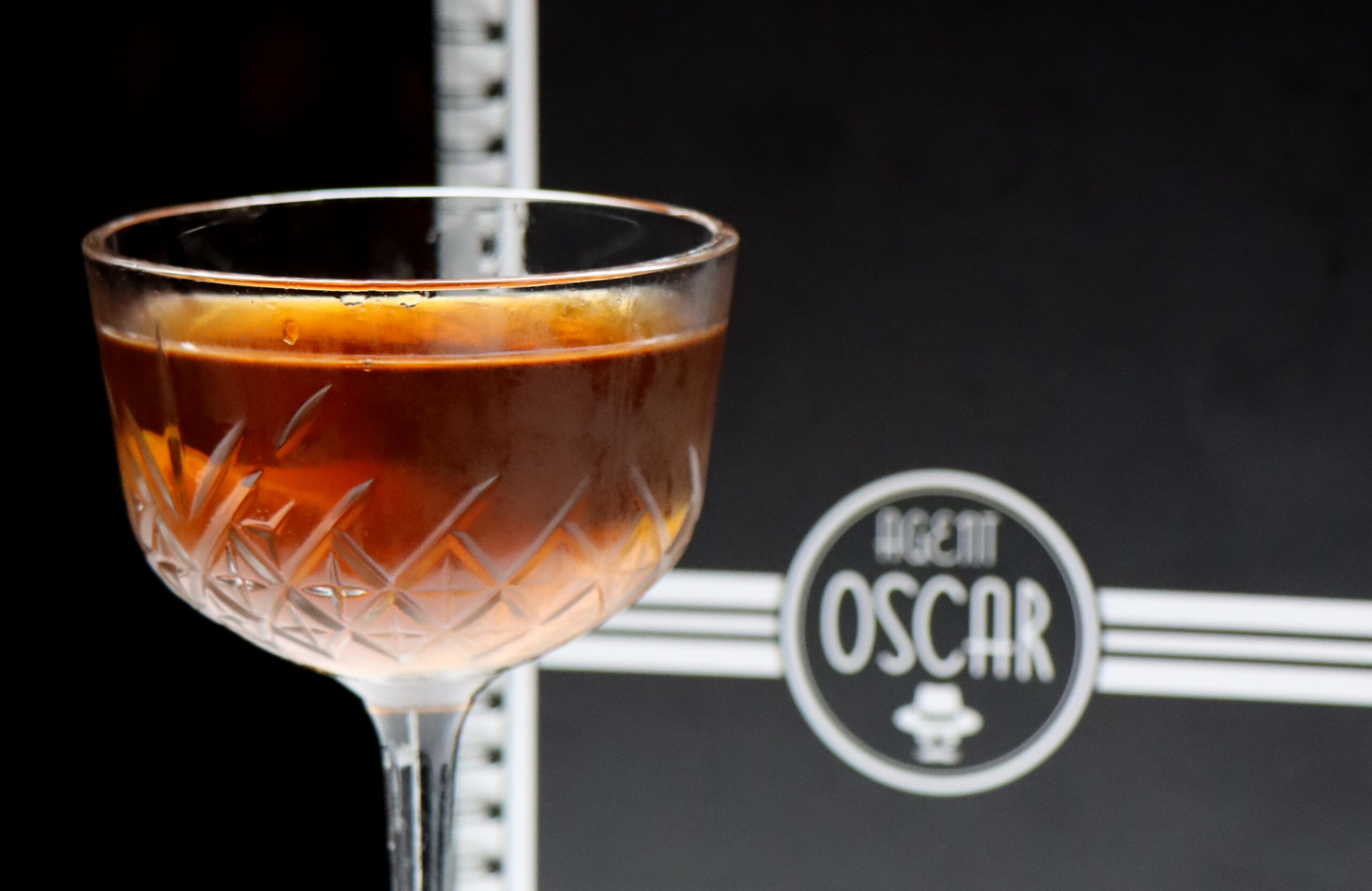 ein klarer, bräunlicher Cocktail steht vor der Menü Karte